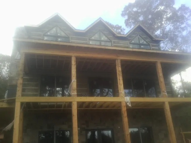 Dormers and porch framing on a large log home under construction — Roof Coating work by our crew in Spring Park