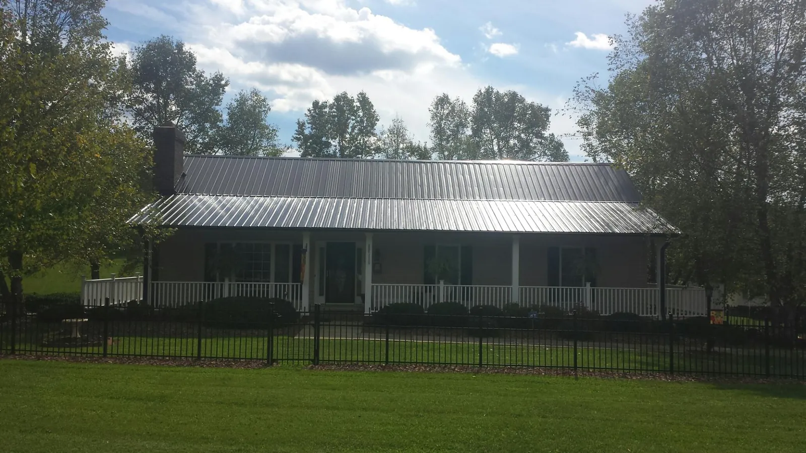 Gray metal roof on a brick ranch with a full width front porch — Gutter Guard Installation work by our crew in Spring Park