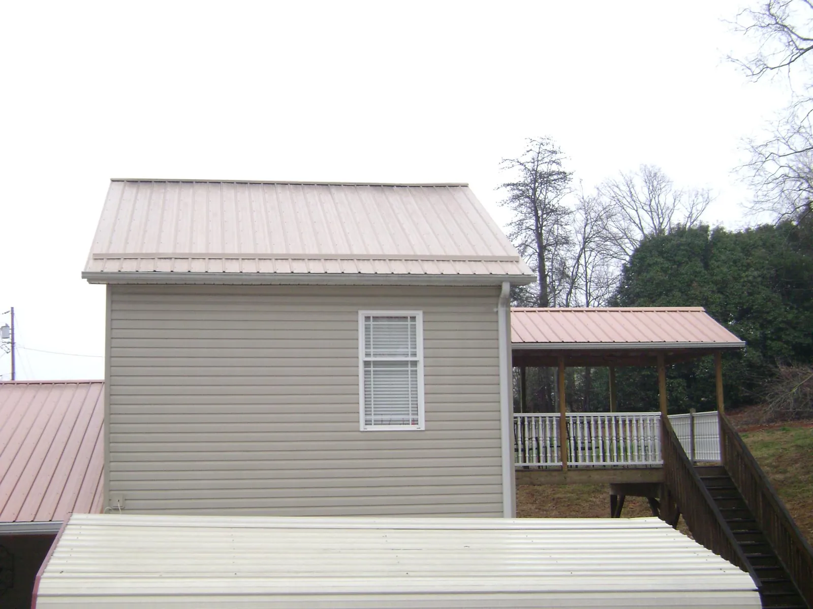 Tan metal roofs on a two story addition and attached porch, from a Roof Replacement job in Spring Park